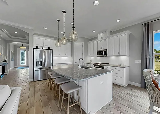 a kitchen with stainless steel appliances granite countertop a kitchen island a stove a refrigerator a center island a table and chairs