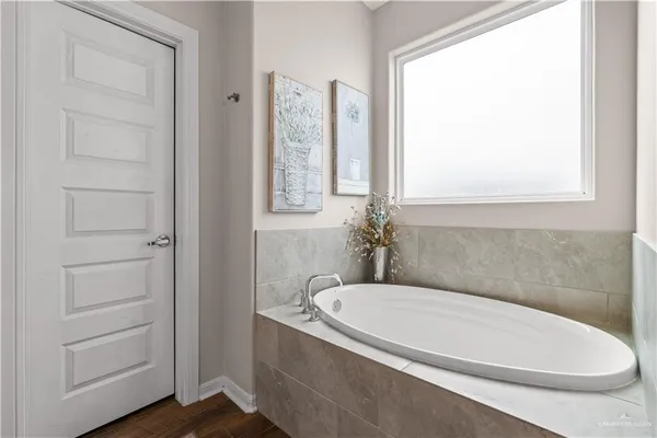 a spacious bathroom with a granite countertop double vanity sink a mirror and a bathtub