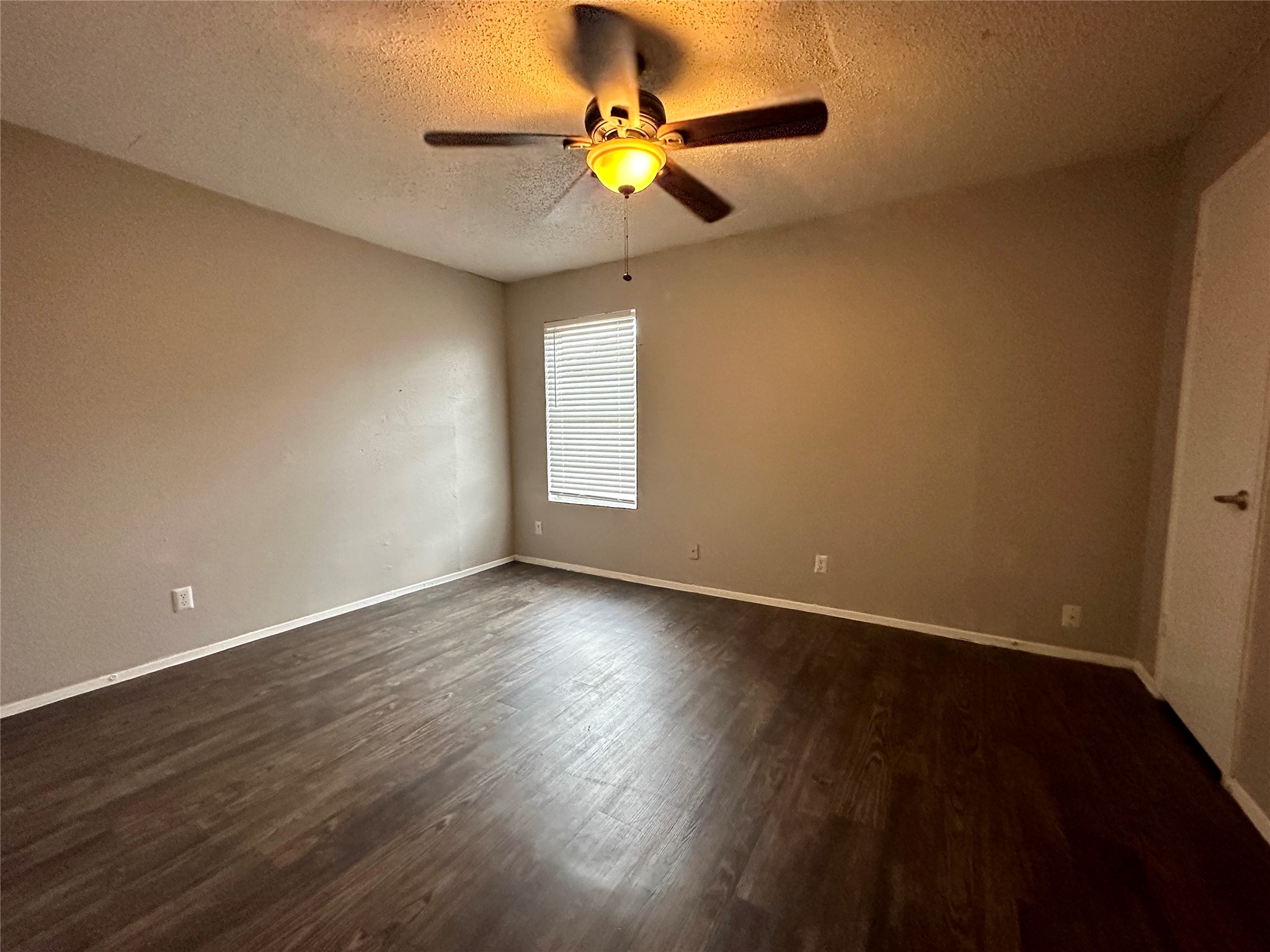 5426 Menchaca Road, Unit 109 Austin, TX 78745 - Photo 9 of 11 Spare room featuring a textured ceiling, dark wood-style flooring, and a ceiling fan