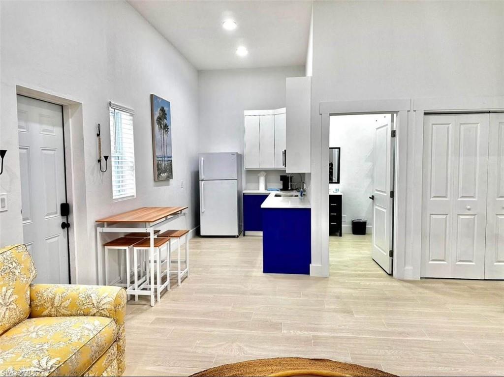 2881 Santa Barbara Boulevard Naples, FL 34116 - Photo 1 of 15 Kitchen with freestanding refrigerator, white cabinetry, light countertops, a high ceiling, and light wood finished floors