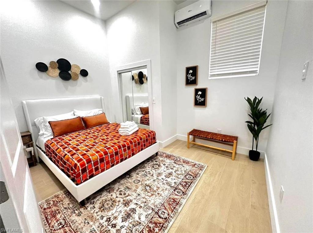 2881 Santa Barbara Boulevard Naples, FL 34116 - Photo 11 of 15 Bedroom featuring a wall mounted AC, wood finished floors, and baseboards