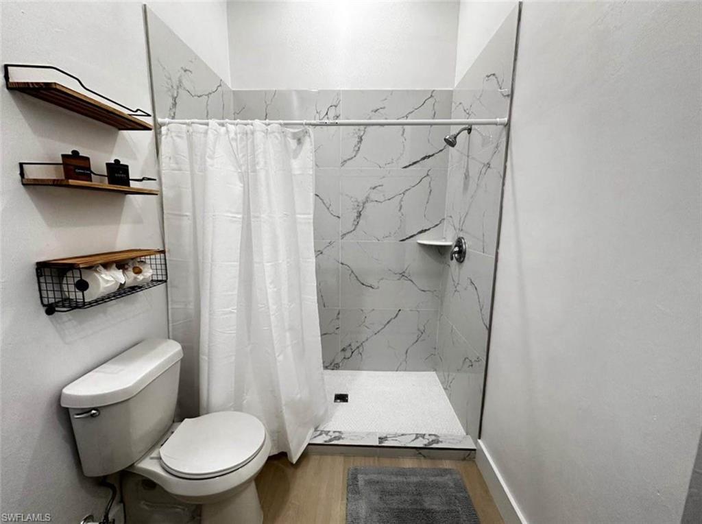 2881 Santa Barbara Boulevard Naples, FL 34116 - Photo 7 of 15 Bathroom with wood finished floors, a shower stall, and toilet