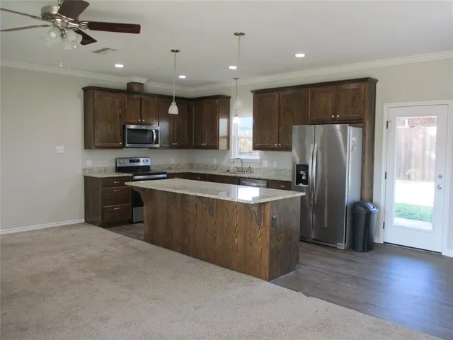 a kitchen with stainless steel appliances granite countertop a refrigerator a sink a stove a microwave and island with wooden floor