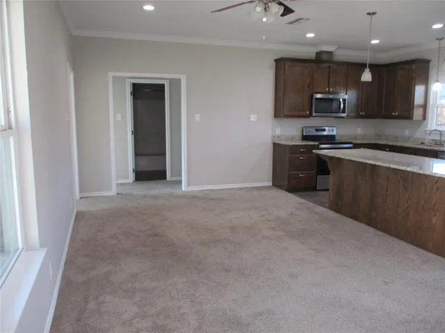 a large kitchen with stainless steel appliances granite countertop a refrigerator a stove top oven a sink and dishwasher