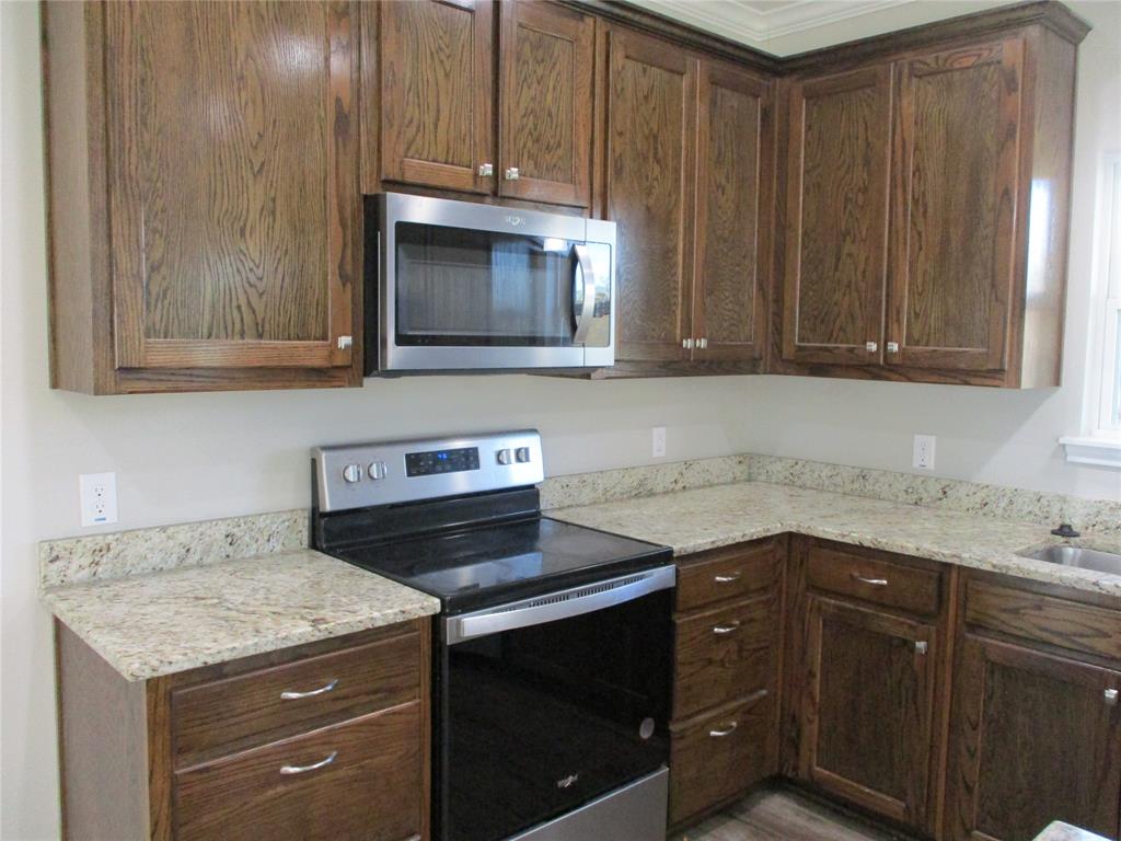 207 Mill Street Emory, TX 75440 - Photo 15 of 34 a kitchen with granite countertop cabinets stove and microwave