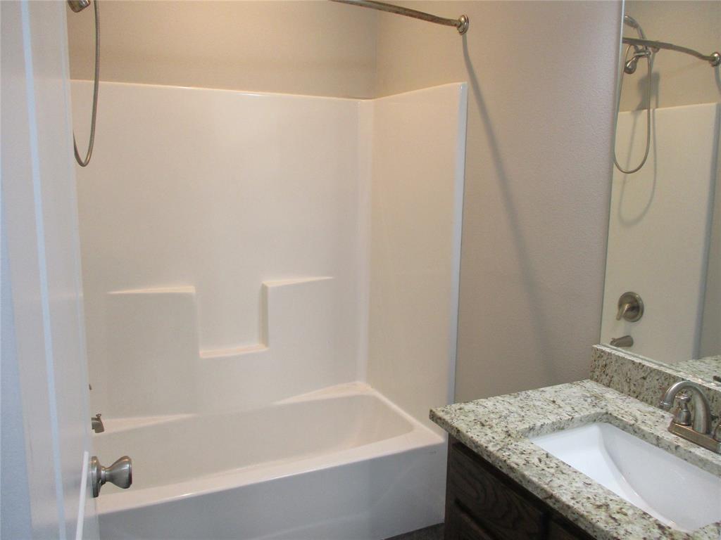 207 Mill Street Emory, TX 75440 - Photo 26 of 34 a bathroom with a granite countertop bathtub shower sink and vanity