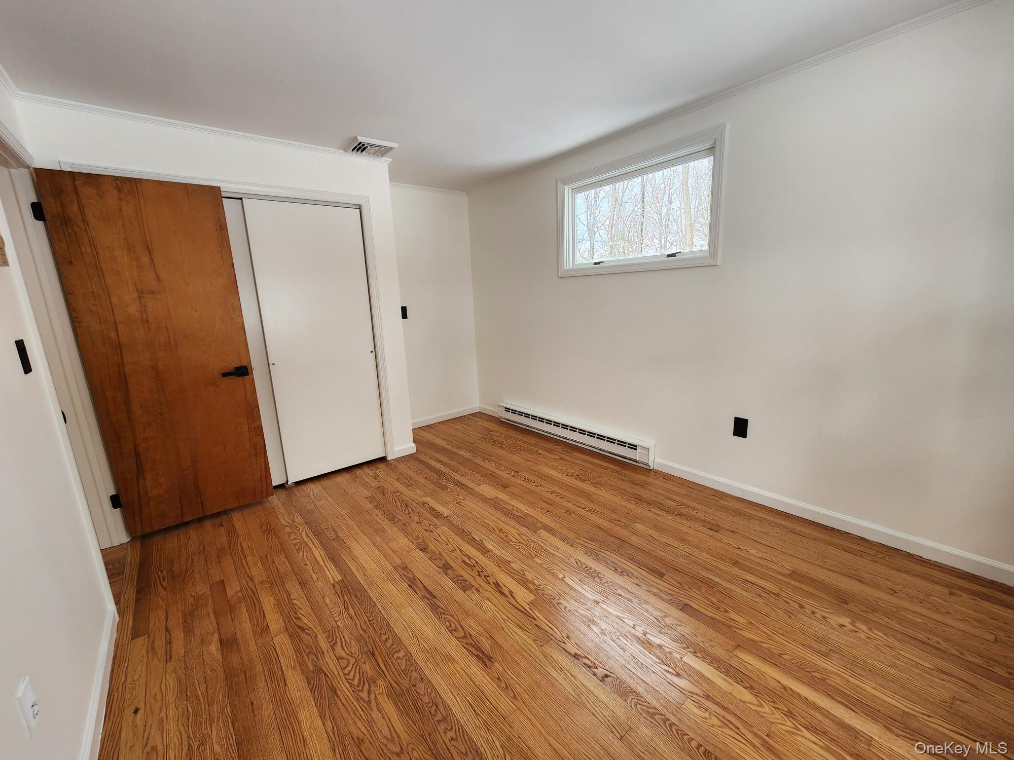 568 River Road Rhinebeck, NY 12572 - Photo 23 of 26 Unfurnished bedroom featuring light wood-style floors, a baseboard radiator, and a closet