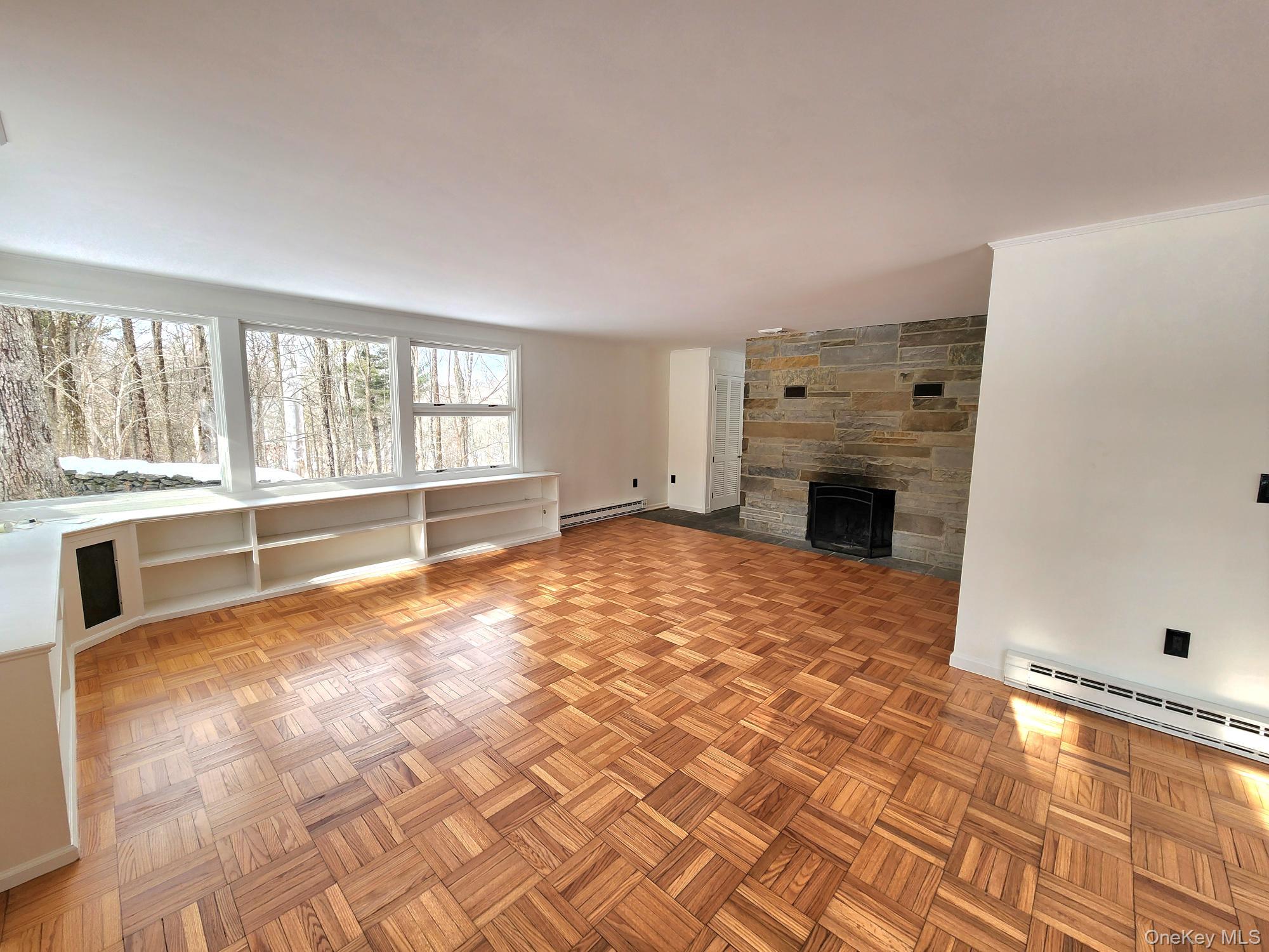 568 River Road Rhinebeck, NY 12572 - Photo 7 of 26 Unfurnished living room featuring a stone fireplace, parquet floors, a baseboard heating unit, and baseboard heating