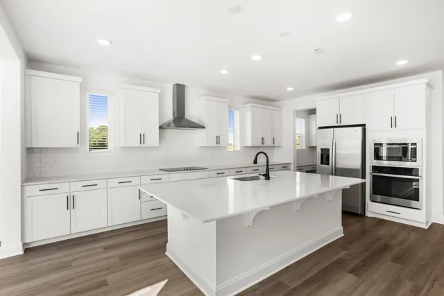 a large kitchen with a center island wooden floor stainless steel appliances and cabinets