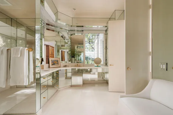 a room with lots of white furniture and a large window