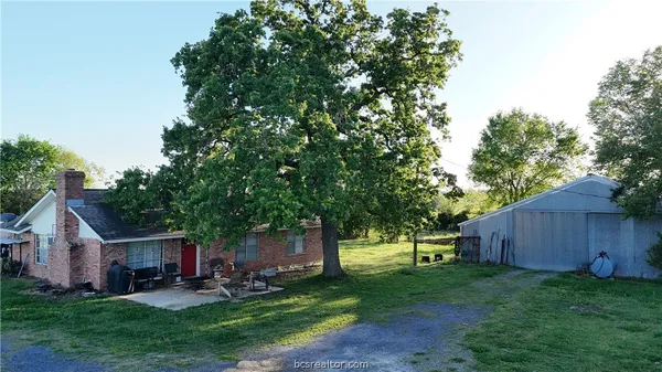 a view of a backyard with table and chairs and a large tree