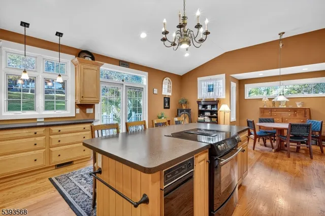 a kitchen with stainless steel appliances granite countertop a stove top oven a dining table and chairs with wooden floor