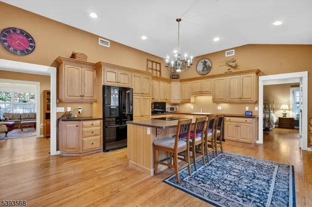 a open kitchen with stainless steel appliances granite countertop a stove top oven a sink dishwasher a dining table and chairs with wooden floor