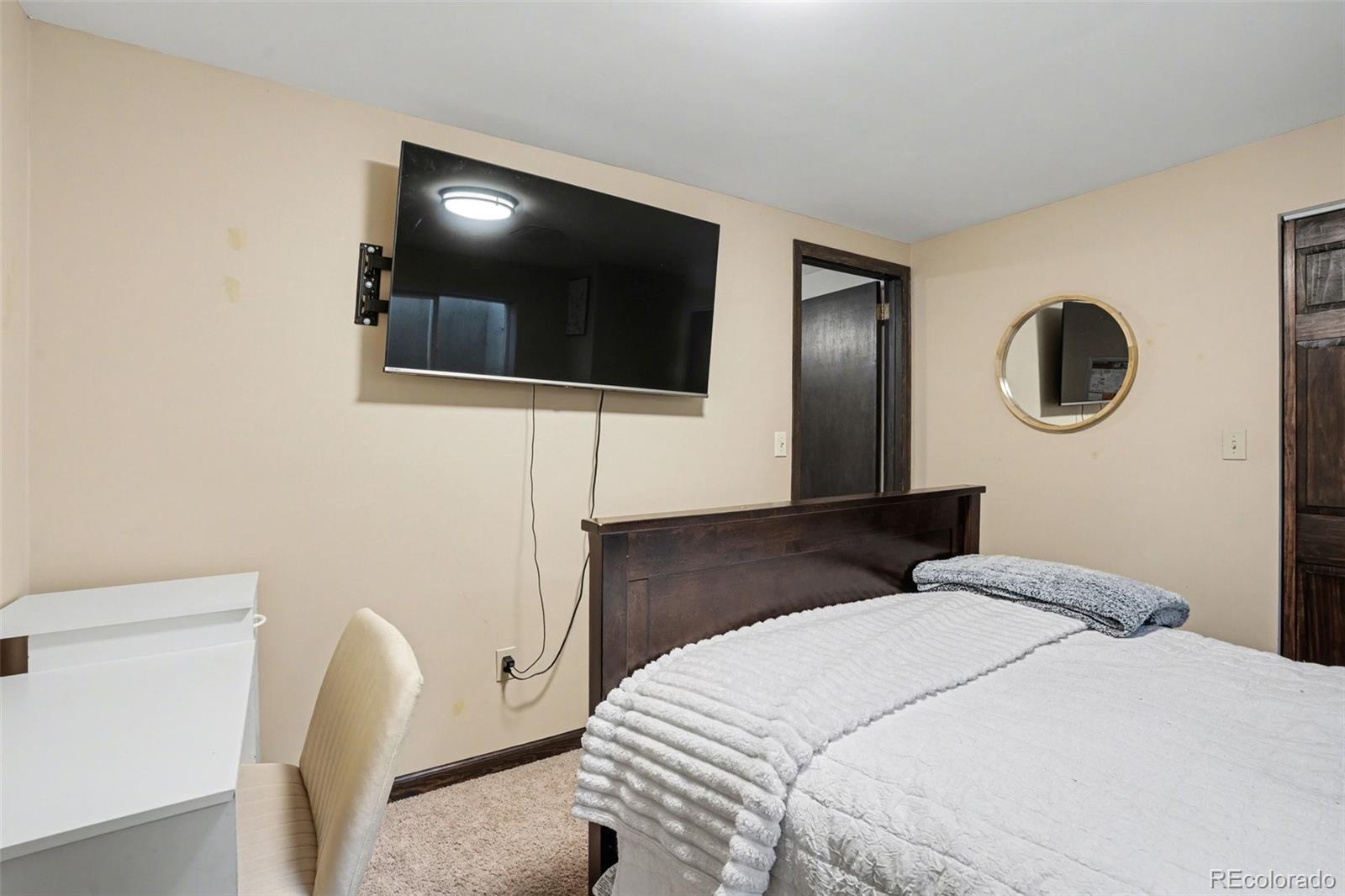 6224 Powell Road Parker, CO 80134 - Photo 24 of 40 a bedroom with a large bed and a flat screen tv