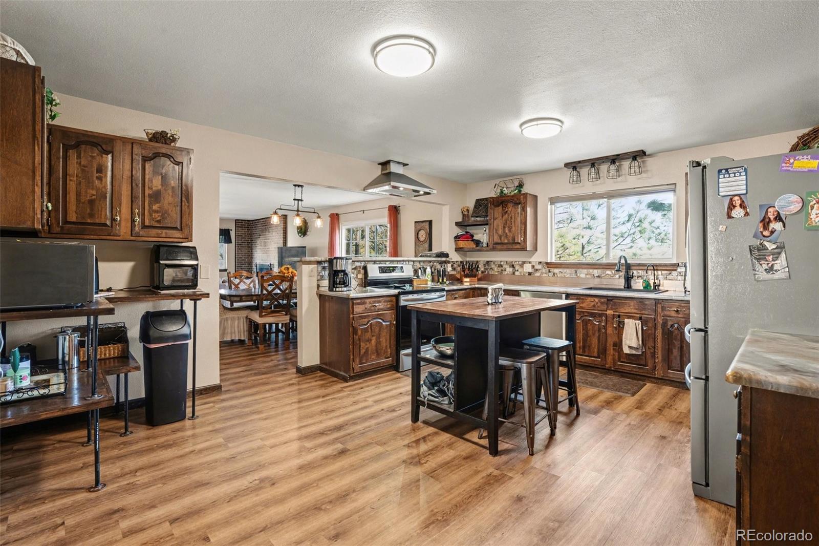 6224 Powell Road Parker, CO 80134 - Photo 8 of 40 a open kitchen with stainless steel appliances granite countertop a stove top oven a sink a dining table and chairs with wooden floor