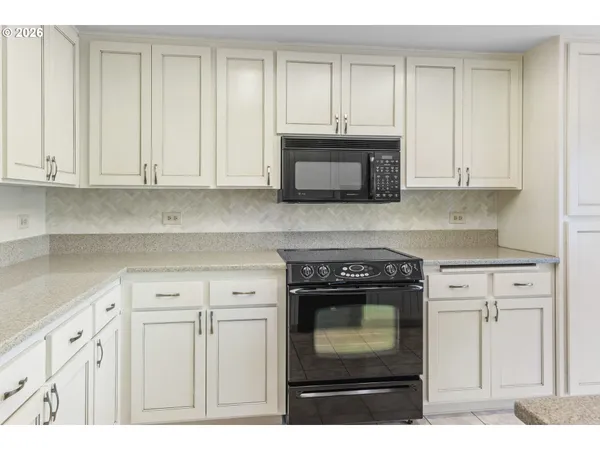 a kitchen with granite countertop white cabinets and stainless steel appliances