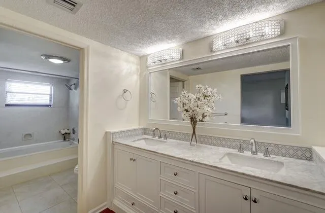 a bathroom with a granite countertop sink mirror and bathtub