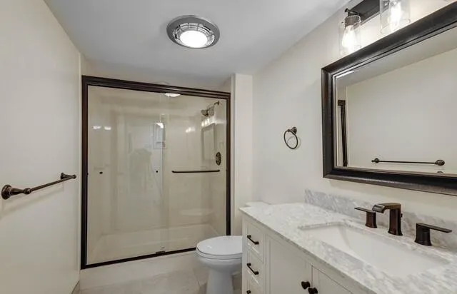 a bathroom with a granite countertop sink toilet mirror and shower