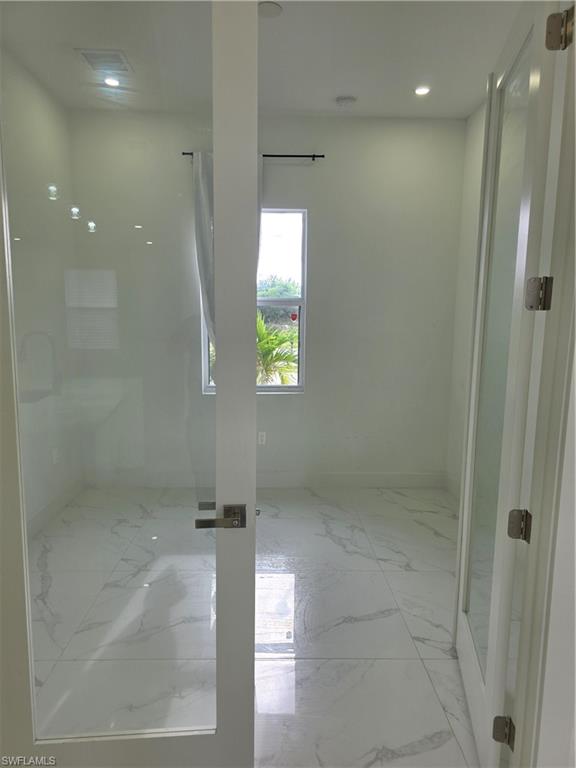 331 Nelson Road North Cape Coral, FL 33993 - Photo 4 of 29 Contemporary kitchen featuring white flat-panel cabinetry, a central island with an integrated sink, and stainless steel appliances