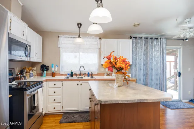 a room with kitchen island a stove a refrigerator and wooden floor