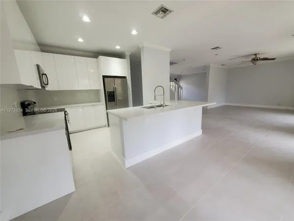 a kitchen with stainless steel appliances a sink a stove a refrigerator a microwave and cabinets