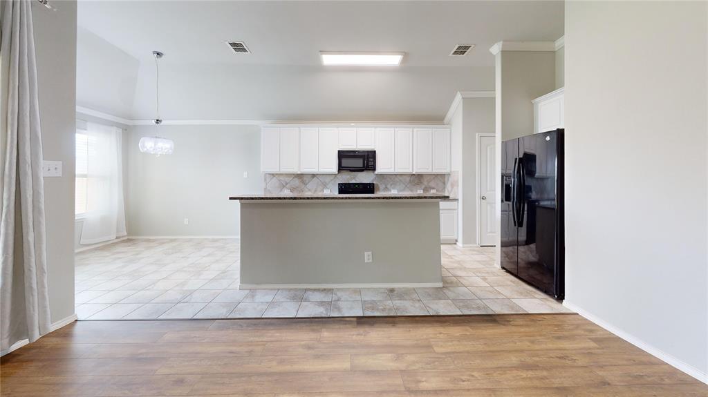 3101 Buckthorn Street Forney, TX 75126 - Photo 32 of 40 Open-concept kitchen with white cabinetry, black appliances, a central island, and tile flooring