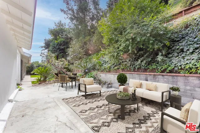 a view of a patio with couches potted plants and large tree