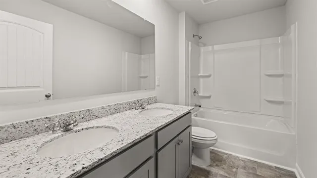 a bathroom with a granite countertop sink a toilet and shower