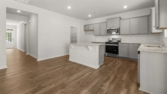 a kitchen with stainless steel appliances granite countertop a stove top oven a sink and white cabinets