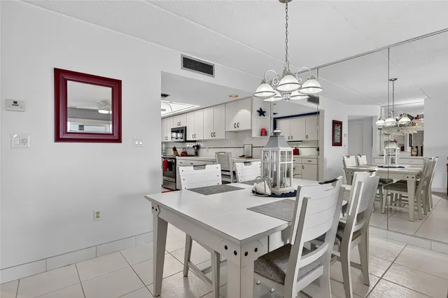 a kitchen that has a lot of white cabinets and stainless steel appliances