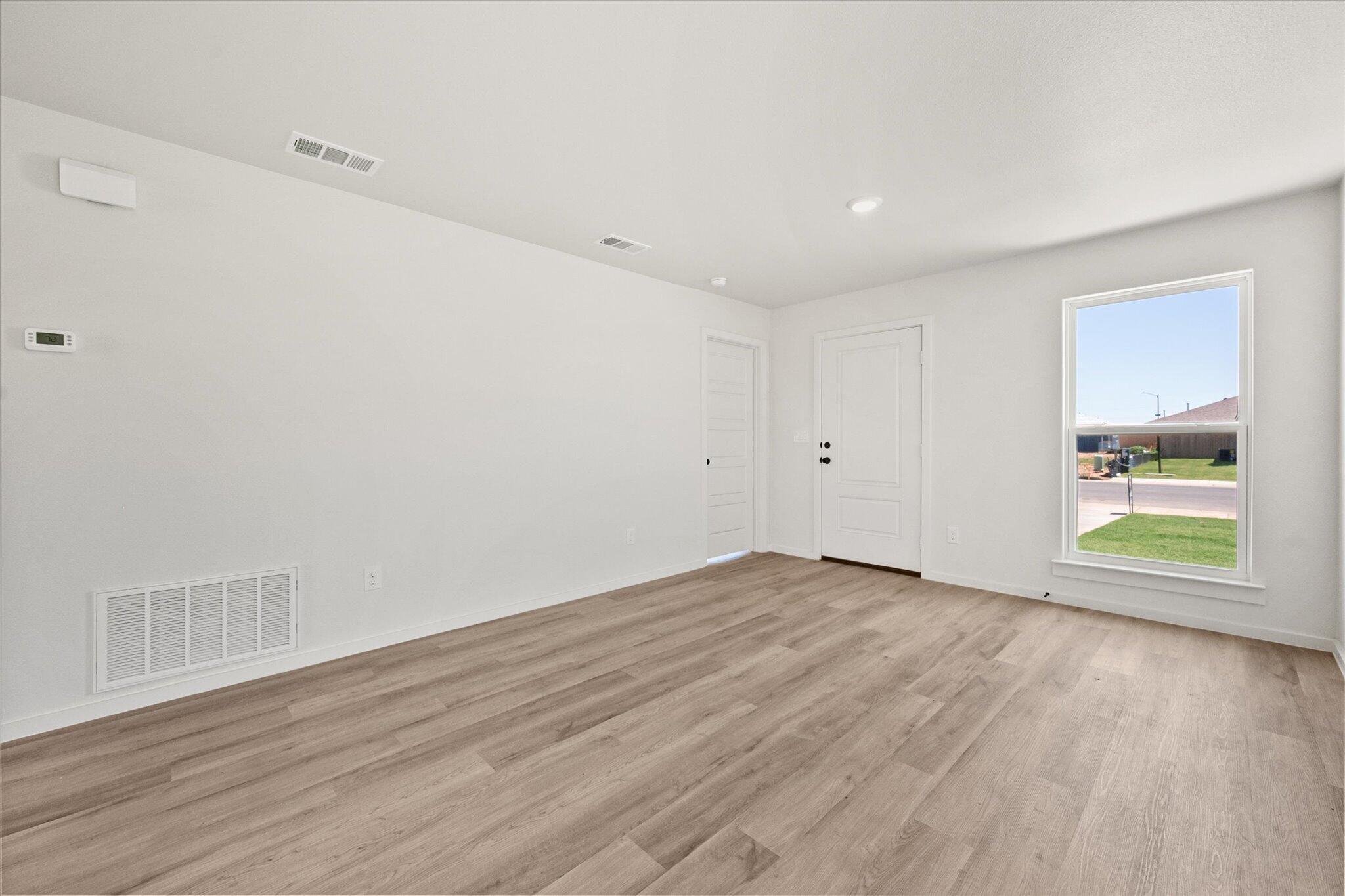 8312 25th Street Lubbock, TX 79407 - Photo 6 of 17 a view of an empty room with wooden floor and a window