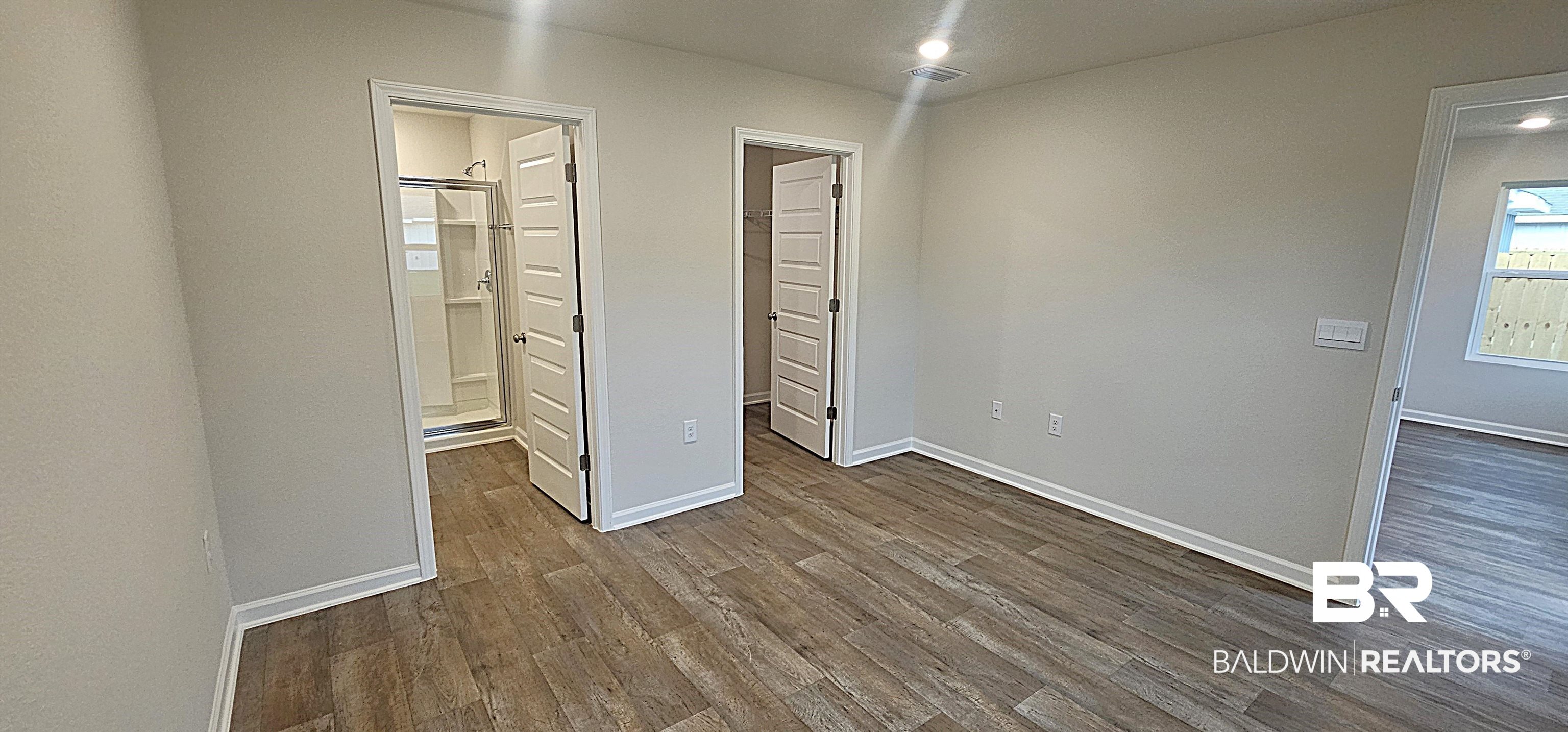 1148 Sweet Laurel Street Foley, AL 36535 - Photo 13 of 18 Unfurnished bedroom featuring a walk in closet, ensuite bath, and dark hardwood / wood-style flooring