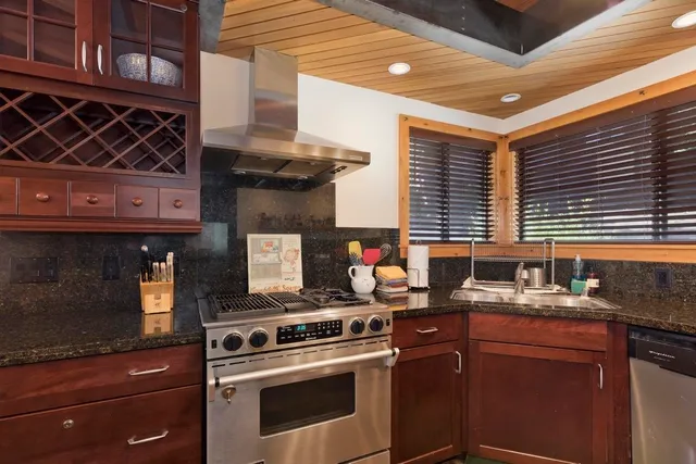 a kitchen with kitchen island granite countertop a sink cabinets and stainless steel appliances