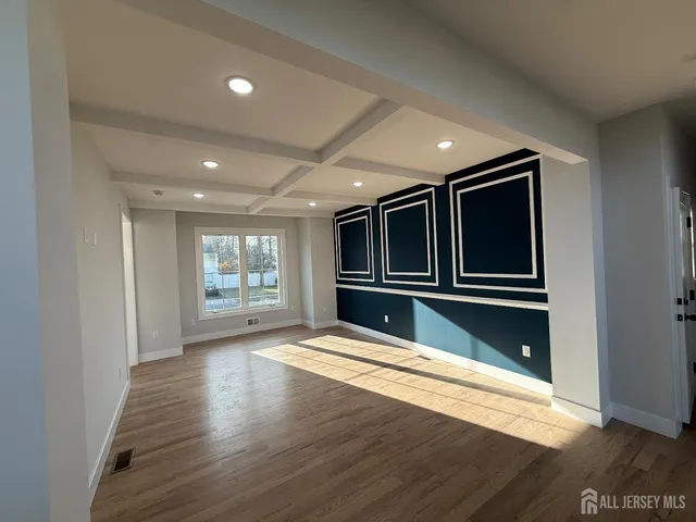a view of an empty room with wooden floor and stairs
