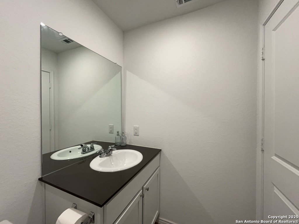 6954 Biotite Ridge Elmendorf, TX 78112 - Photo 22 of 39 a bathroom with a sink and a mirror