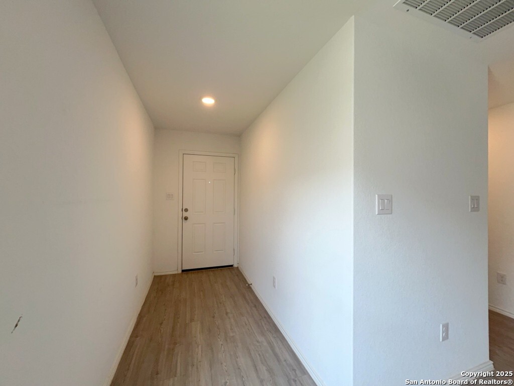 6954 Biotite Ridge Elmendorf, TX 78112 - Photo 26 of 39 a view of a hallway with wooden floor
