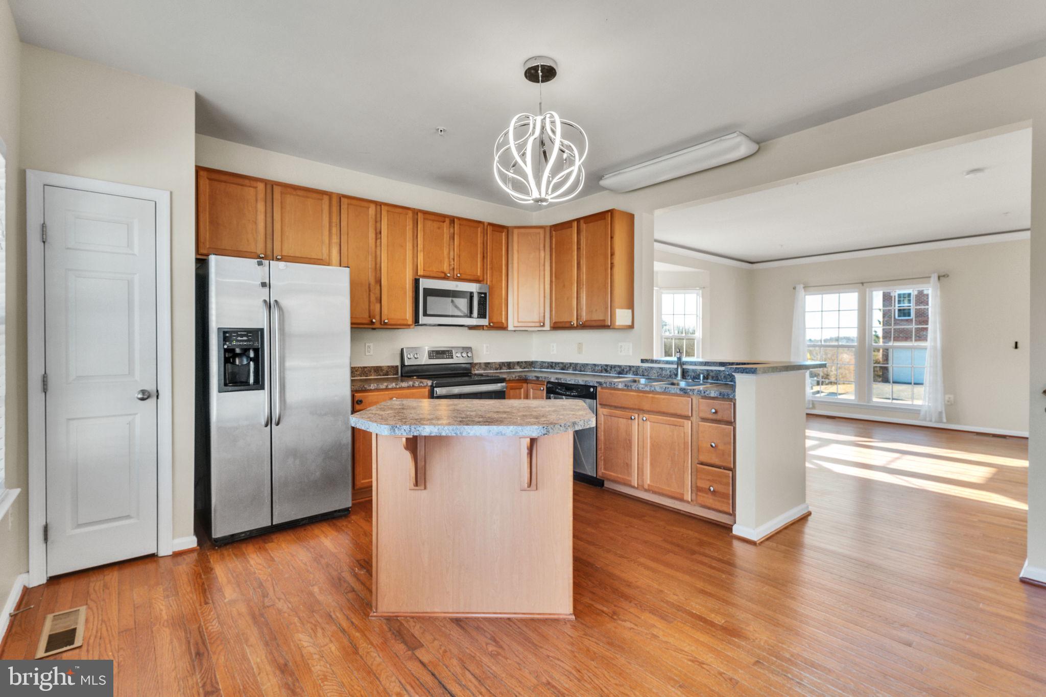 25501 Joy Lane Damascus, MD 20872 - Photo 16 of 35 a kitchen with granite countertop a refrigerator a stove top oven and wooden floors