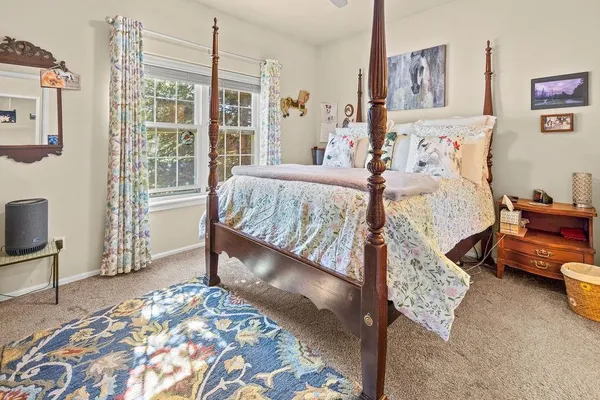 a bed sitting in a bedroom next to a window with a lamp and a rug