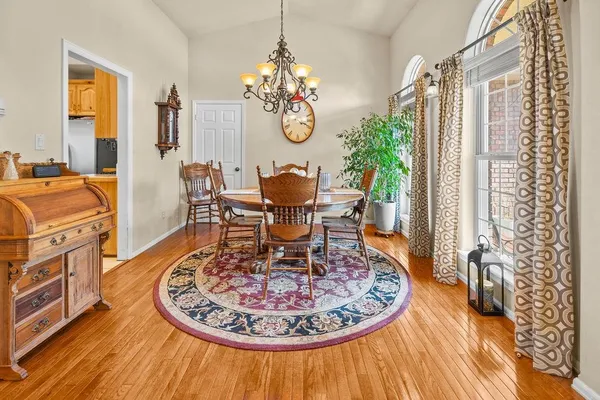a dining room with chandelier fan wooden floor and a rug