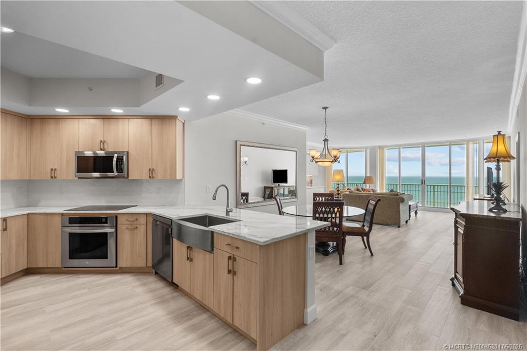 8600 South Ocean Drive, Unit PH5 Jensen Beach, FL 34957 - Photo 4 of 49 a open kitchen with stainless steel appliances granite countertop a stove top oven a sink dishwasher a dining table and chairs with wooden floor