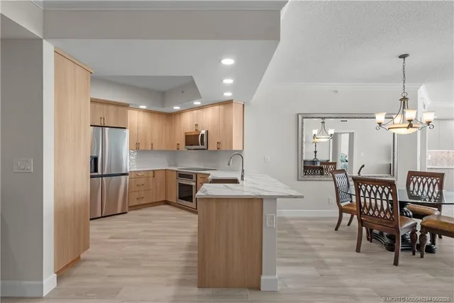a kitchen with stainless steel appliances kitchen island granite countertop a table chairs and a refrigerator