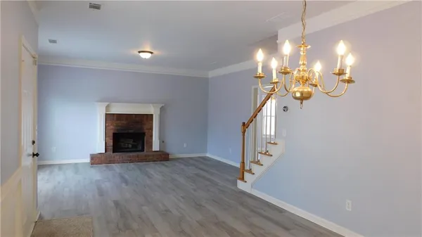 a view of an empty room with wooden floor and a fireplace