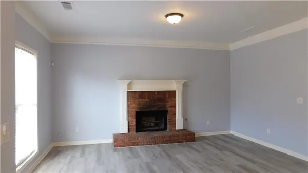 a view of an empty room with wooden floor fireplace and a window