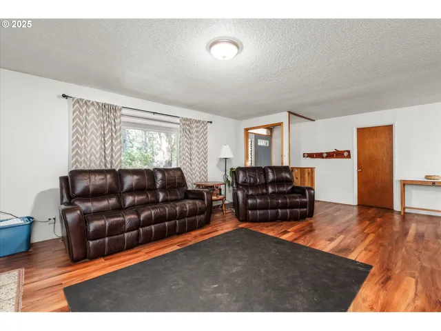 a view of a backyard with plants and large trees with wooden fence