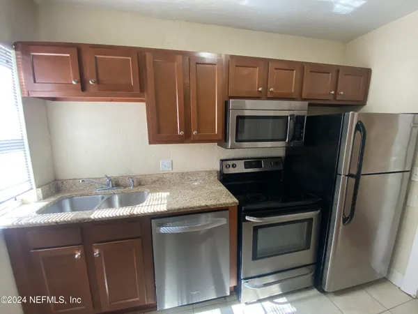 a kitchen with granite countertop a refrigerator stove and microwave