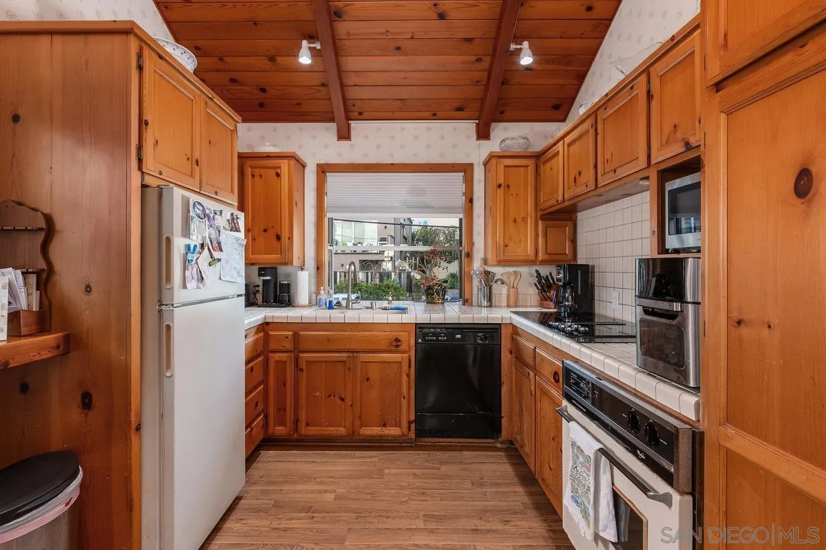 1366 Neptune Avenue Encinitas, CA 92024 - Photo 32 of 48 a kitchen with stainless steel appliances granite countertop a refrigerator a sink dishwasher and wooden cabinets with wooden floor