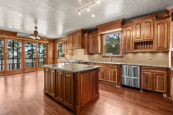a kitchen with stainless steel appliances granite countertop a stove a sink dishwasher and a microwave oven with wooden floor