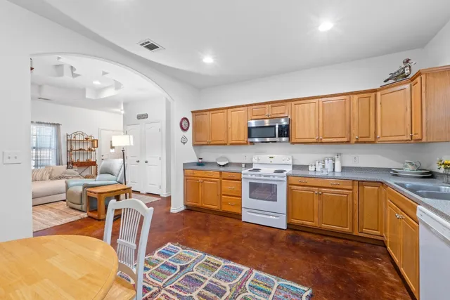 a kitchen with stainless steel appliances granite countertop a stove top oven a sink dishwasher a dining table and chairs with wooden floor