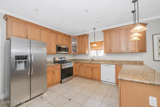 a kitchen with granite countertop stainless steel appliances a stove a sink a refrigerator and cabinets