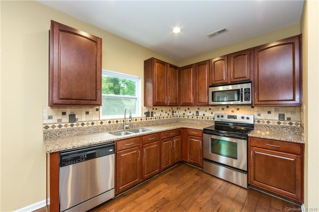 1132 Spicewood Pines Road Fort Mill, SC 29708 - Photo 13 of 24 a kitchen with stainless steel appliances granite countertop wooden cabinets stove top oven and sink